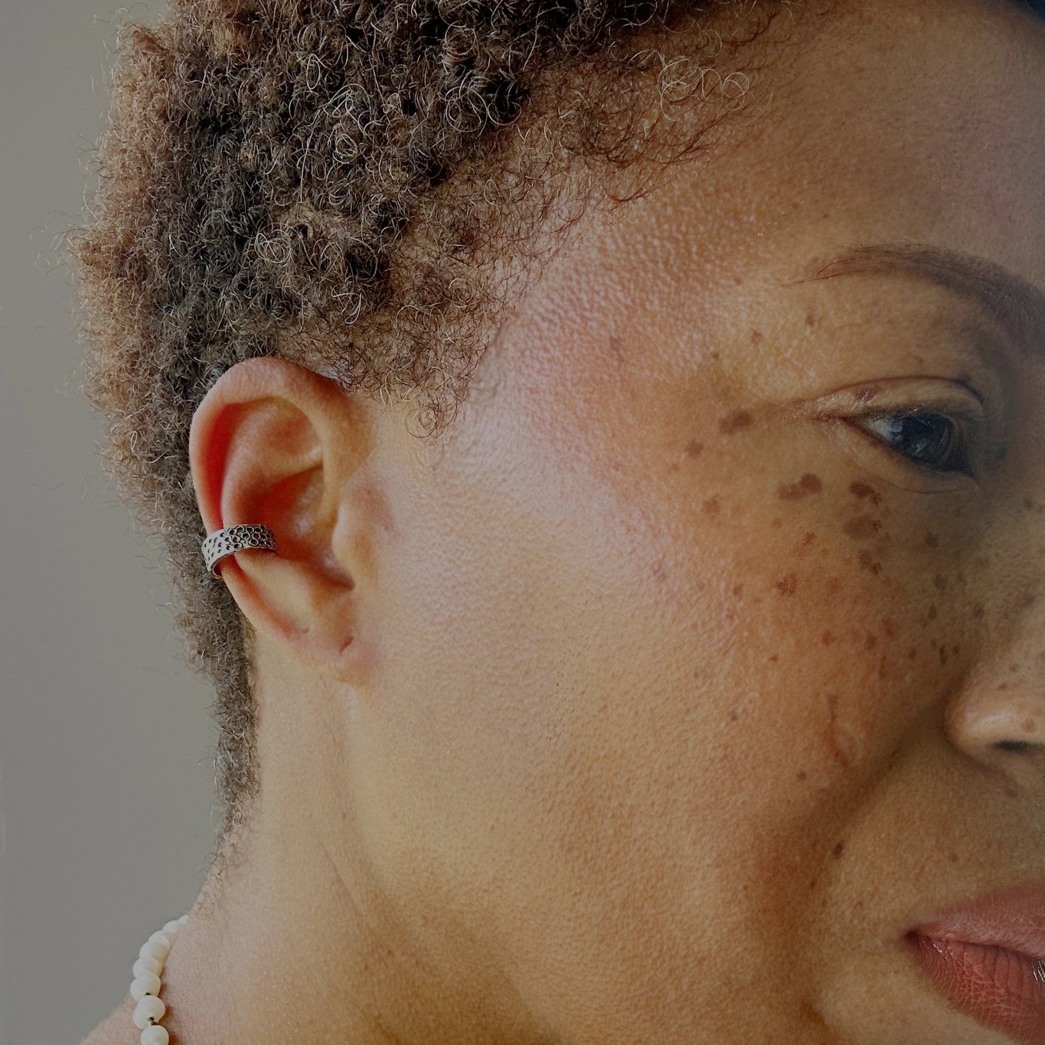 Earcuff Niara en argent 925 oxydé, texture perforée façon cratères porté, collection Keloïd EMIKemi