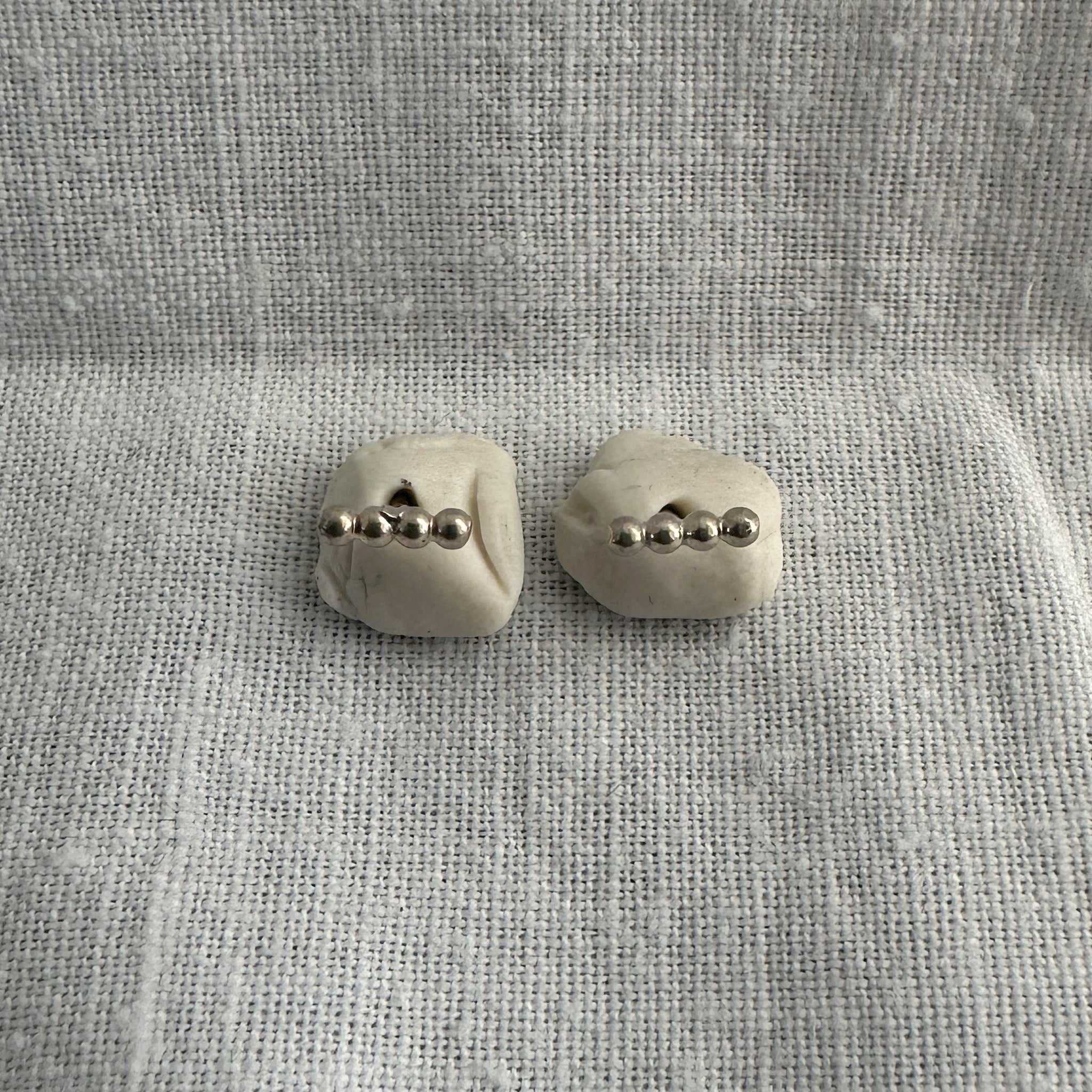 "Détail des boucles d'oreilles Modibo - perles argent alignées design moderne"