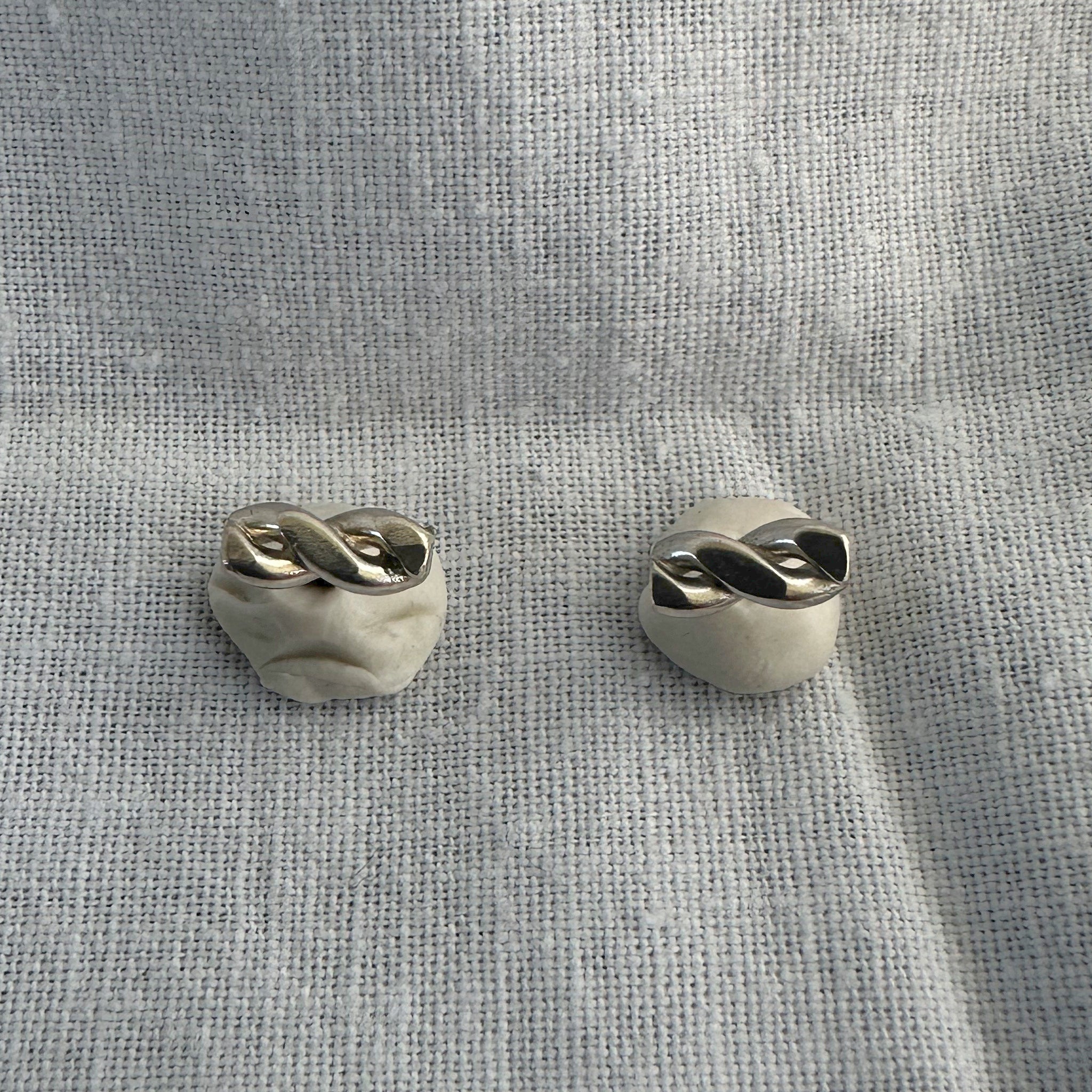 "Détail des boucles d'oreilles torsadées Nilaja - texture argent raffinée"